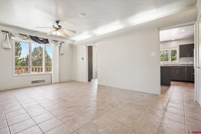 unfurnished room featuring visible vents, ceiling fan, a sink, and light tile patterned flooring