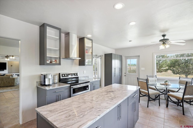 kitchen featuring a center island, light tile patterned floors, gray cabinets, wall chimney range hood, and stainless steel electric range