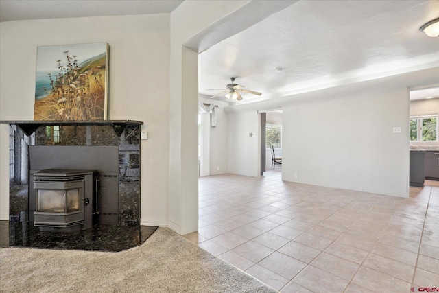 living area featuring a wood stove, ceiling fan, and tile patterned flooring