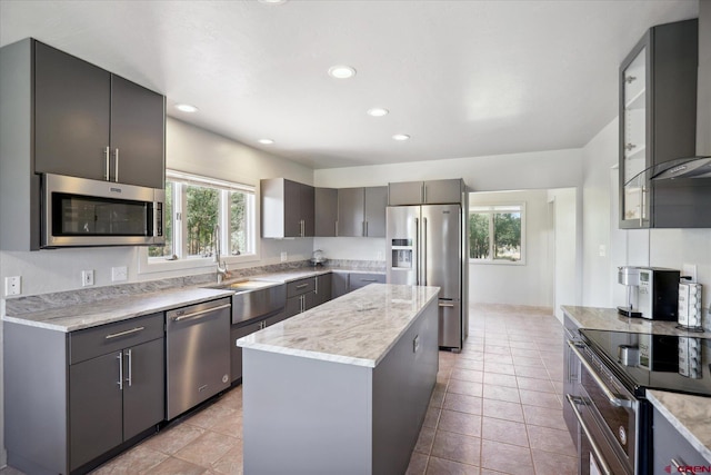 kitchen featuring a center island, light tile patterned floors, recessed lighting, appliances with stainless steel finishes, and a sink