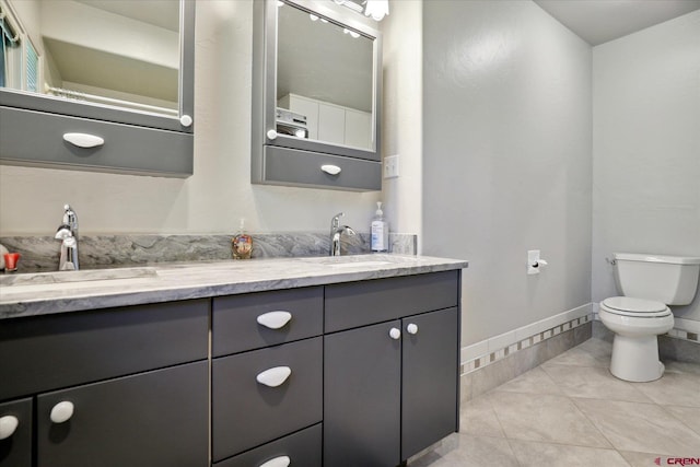 bathroom featuring toilet, double vanity, a sink, and tile patterned floors