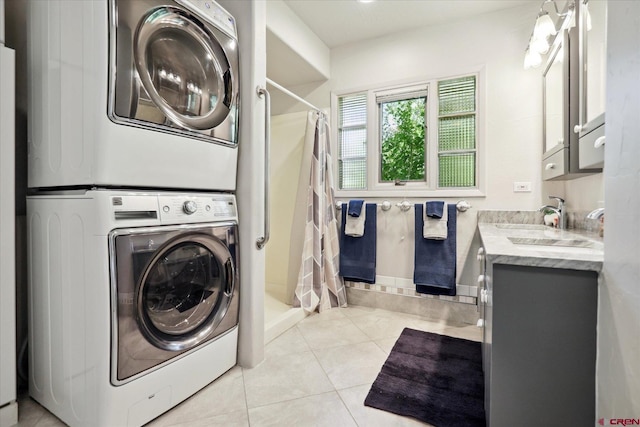 laundry area with light tile patterned flooring, laundry area, a sink, baseboards, and stacked washer / drying machine