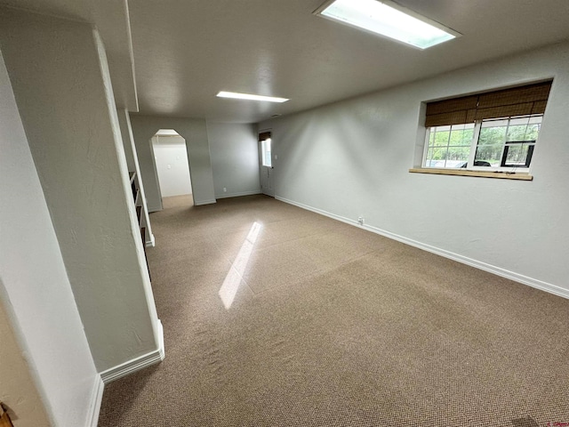 carpeted empty room with arched walkways and baseboards