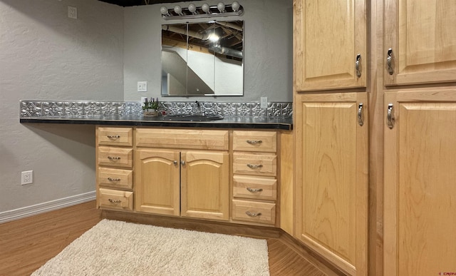 bathroom featuring a textured wall, baseboards, and wood finished floors