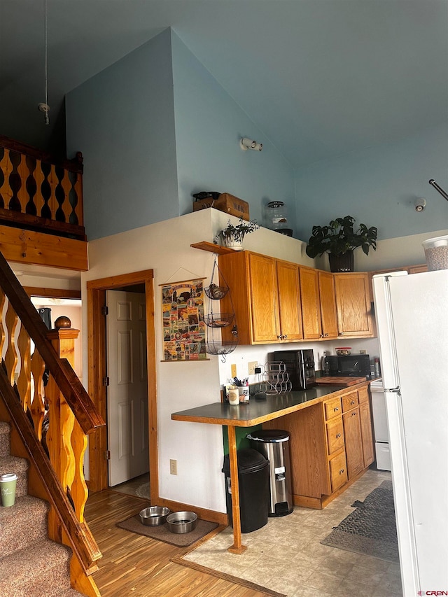 kitchen featuring white refrigerator, high vaulted ceiling, and light hardwood / wood-style floors