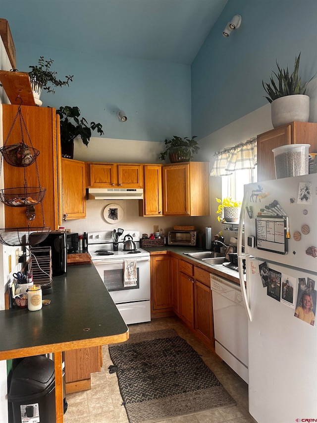 kitchen with light tile patterned floors, white appliances, sink, a kitchen breakfast bar, and high vaulted ceiling