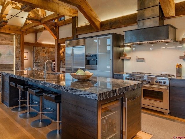 kitchen with a breakfast bar, sink, a large island, dark stone counters, and premium appliances