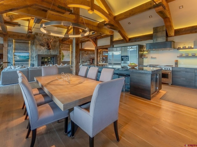 dining room featuring hardwood / wood-style floors, lofted ceiling with beams, and a fireplace