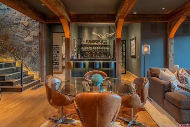 wine cellar with beamed ceiling, wood-type flooring, and indoor bar