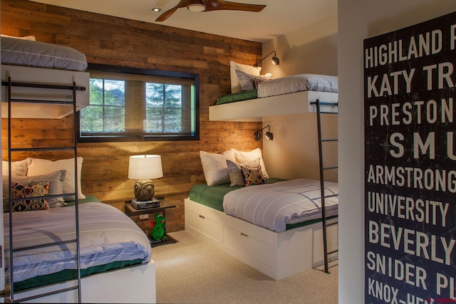 bedroom with carpet flooring, wooden walls, and ceiling fan