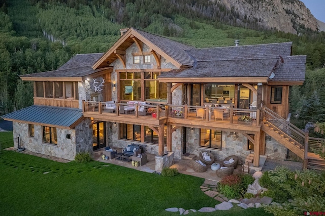 back of property featuring a lawn, a mountain view, an outdoor hangout area, a patio, and a balcony