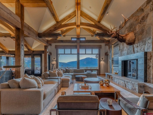 living room with plenty of natural light, a mountain view, a stone fireplace, and beam ceiling