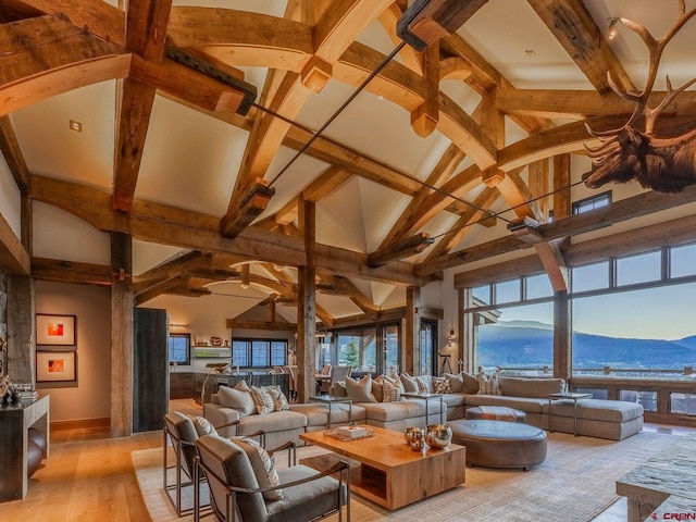 living room featuring a mountain view, hardwood / wood-style floors, high vaulted ceiling, and beam ceiling