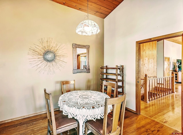 dining space featuring hardwood / wood-style floors, high vaulted ceiling, and wooden ceiling