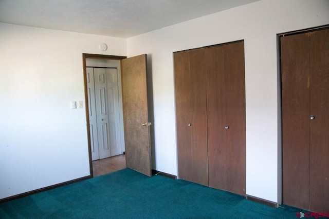 unfurnished bedroom featuring two closets and dark carpet