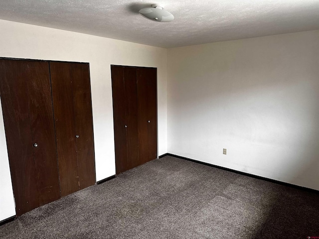 304 N 9th St Unit 5A, Gunnison, CO 81230 - unfurnished bedroom with carpet flooring, baseboards, two closets, and a textured ceiling