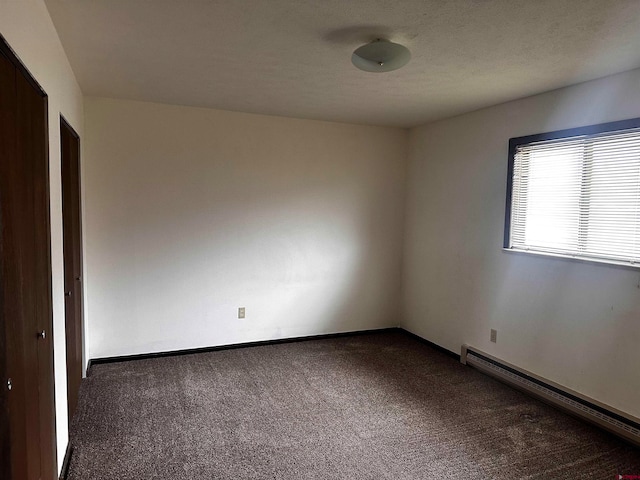 carpeted empty room featuring baseboard heating