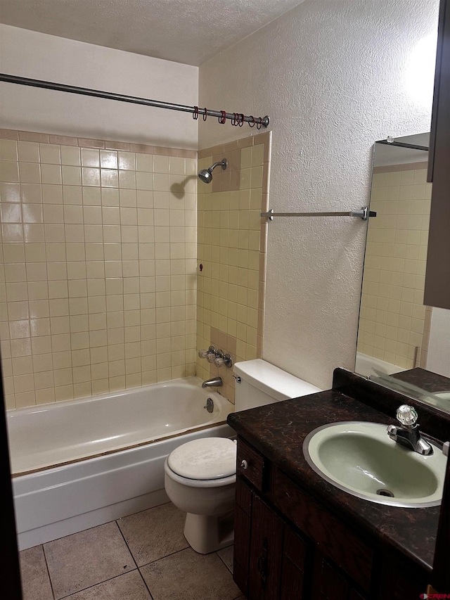 full bathroom featuring toilet, tile patterned floors, a textured ceiling, tiled shower / bath combo, and vanity