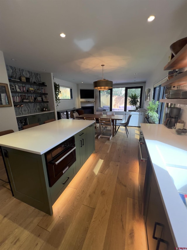 kitchen featuring recessed lighting, open floor plan, light countertops, and light wood finished floors