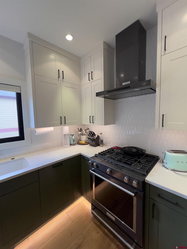 kitchen with a sink, gas stove, white cabinets, light countertops, and extractor fan