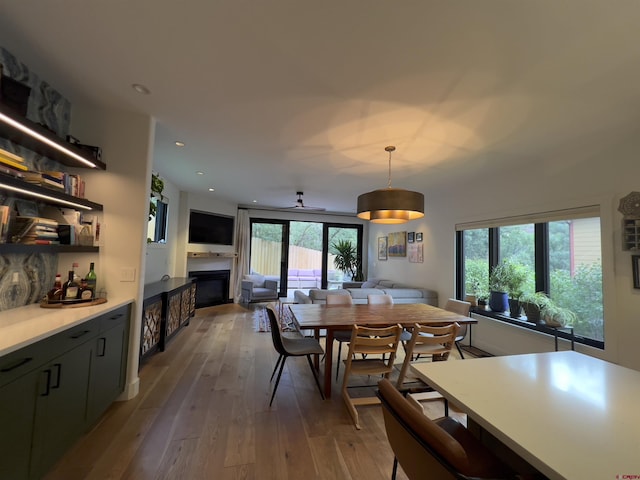 dining area with recessed lighting, a glass covered fireplace, and hardwood / wood-style flooring