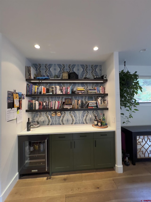 bar with baseboards, wine cooler, recessed lighting, light wood-style floors, and a bar