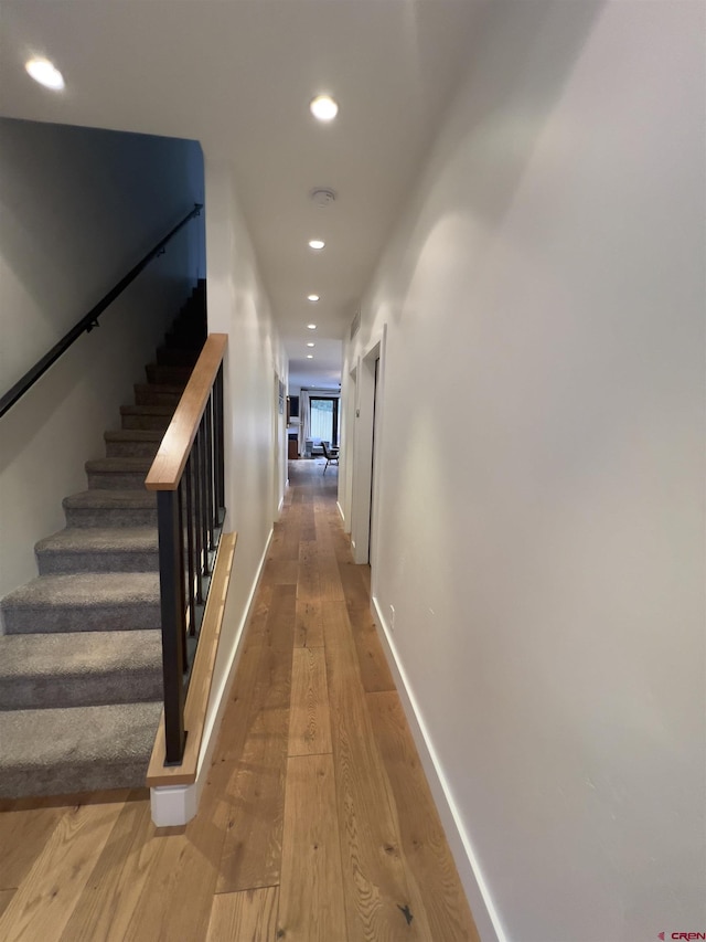 hall featuring recessed lighting, stairs, baseboards, and wood finished floors