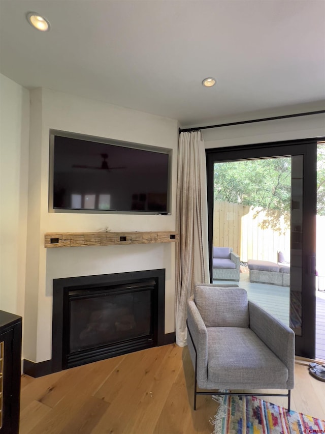 sitting room with recessed lighting, baseboards, wood finished floors, and a glass covered fireplace