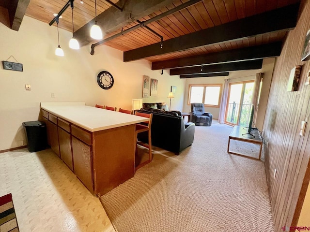kitchen featuring brown cabinets, beam ceiling, a peninsula, a kitchen bar, and wood ceiling