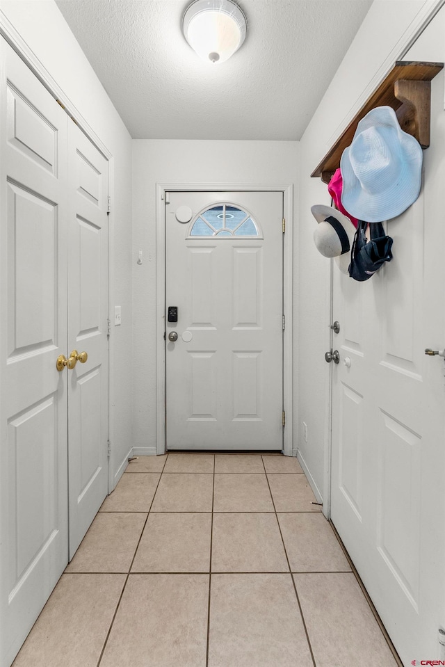 doorway with a textured ceiling and light tile patterned floors