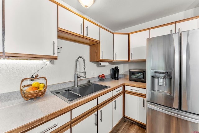 kitchen with hardwood / wood-style floors, stainless steel fridge with ice dispenser, white cabinetry, and sink