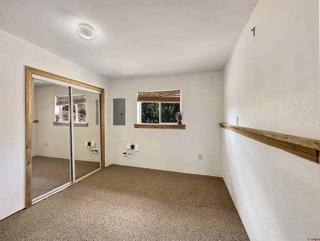 unfurnished bedroom with carpet, electric panel, a closet, and multiple windows