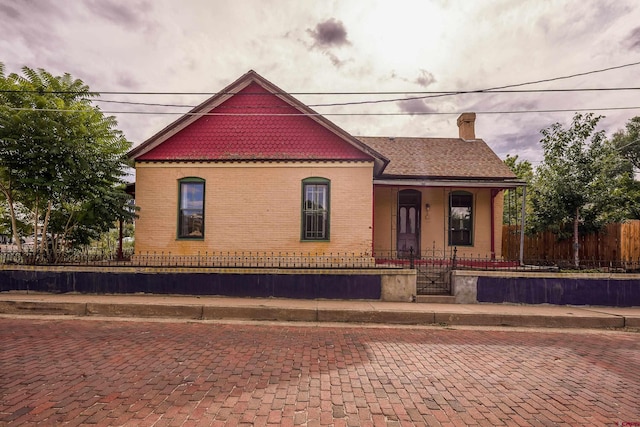 view of front of house with brick siding, a fenced front yard, and a chimney