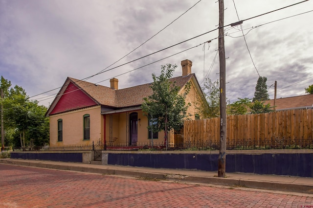 view of front of property featuring a fenced front yard, brick siding, and a chimney