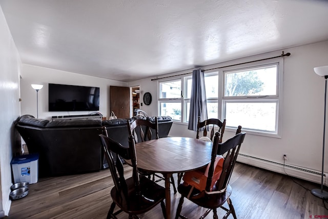 dining space with a baseboard heating unit and dark wood-type flooring