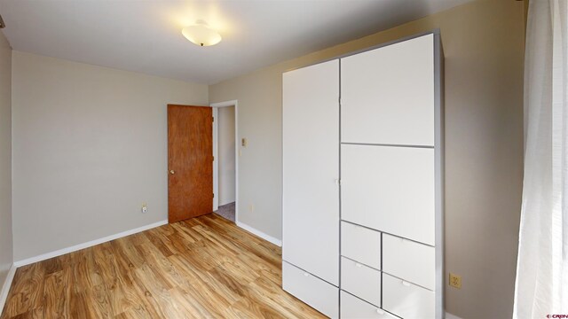 unfurnished bedroom with light wood-type flooring and a closet