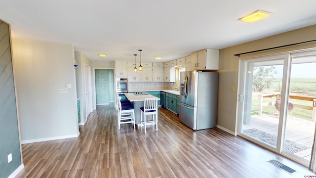 kitchen featuring hardwood / wood-style floors, a kitchen bar, decorative light fixtures, a kitchen island, and stainless steel fridge with ice dispenser