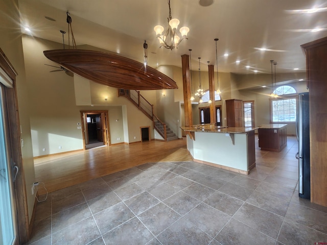 kitchen featuring an inviting chandelier, decorative light fixtures, stainless steel fridge, wood-type flooring, and a breakfast bar area