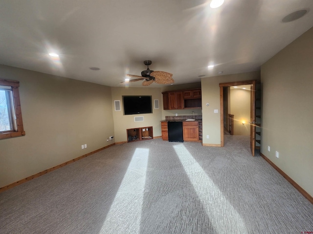 unfurnished living room featuring light colored carpet, sink, and ceiling fan