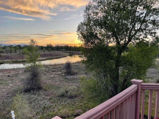 yard at dusk featuring a water view