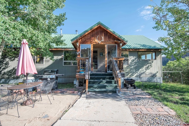 view of front of house with fence, metal roof, and a patio