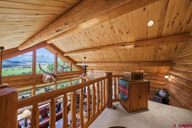 hall with lofted ceiling with beams, log walls, wooden ceiling, a mountain view, and carpet