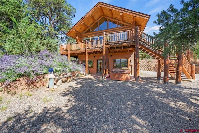 back of house with a hot tub and a deck