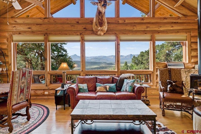 sunroom / solarium with ceiling fan, a wealth of natural light, a mountain view, and vaulted ceiling with beams