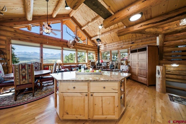 kitchen featuring light wood-type flooring, decorative light fixtures, a kitchen island, light stone counters, and wooden ceiling