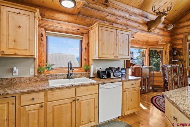 kitchen with light hardwood / wood-style floors, light brown cabinetry, white dishwasher, and rustic walls