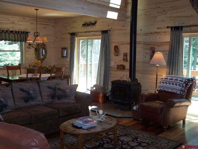 living area featuring plenty of natural light, wood walls, a wood stove, and wood finished floors