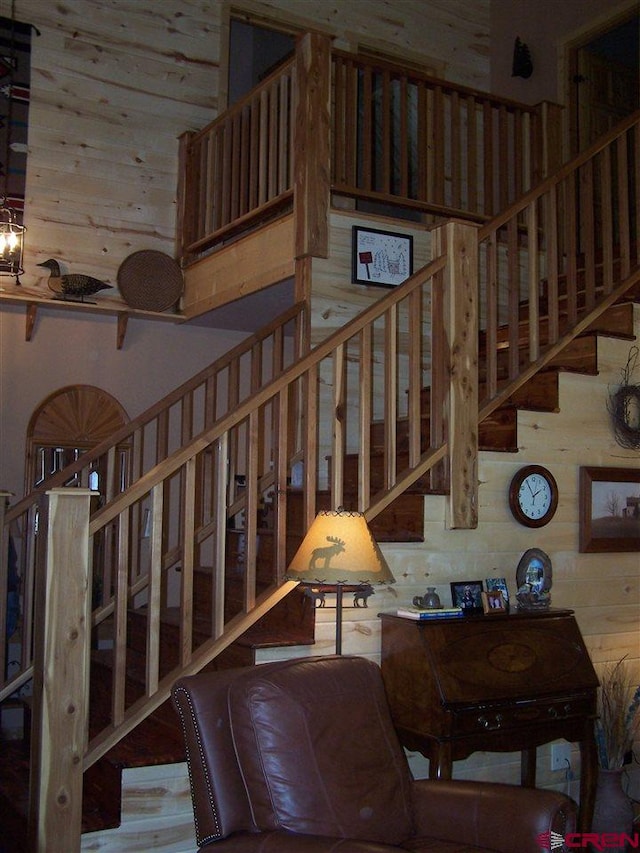 staircase with wooden walls and a high ceiling