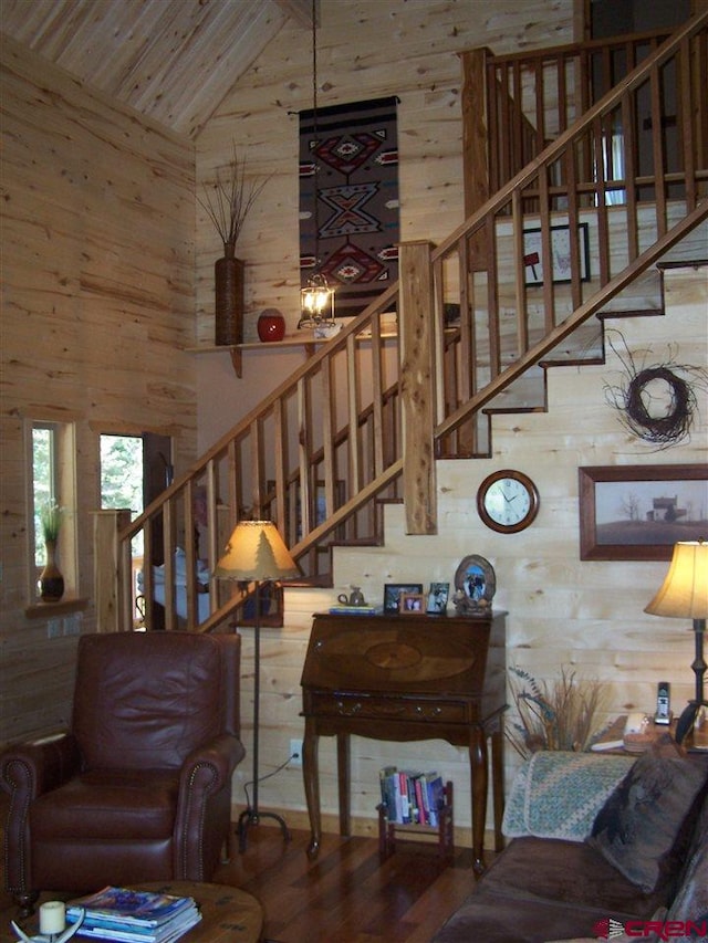 living room with high vaulted ceiling, wooden walls, and stairs