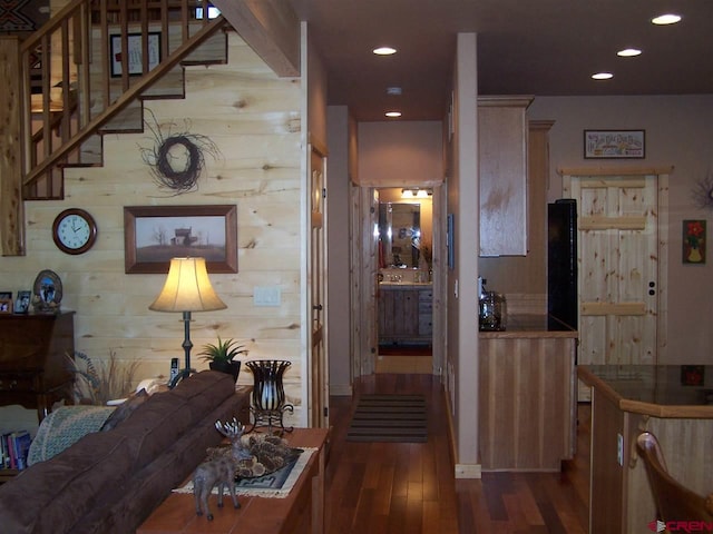 corridor featuring recessed lighting, dark wood finished floors, stairs, and wood walls